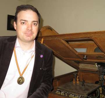 David Vivancos, wearing a medal, seated beside the original El Ajedrecista chess automaton.